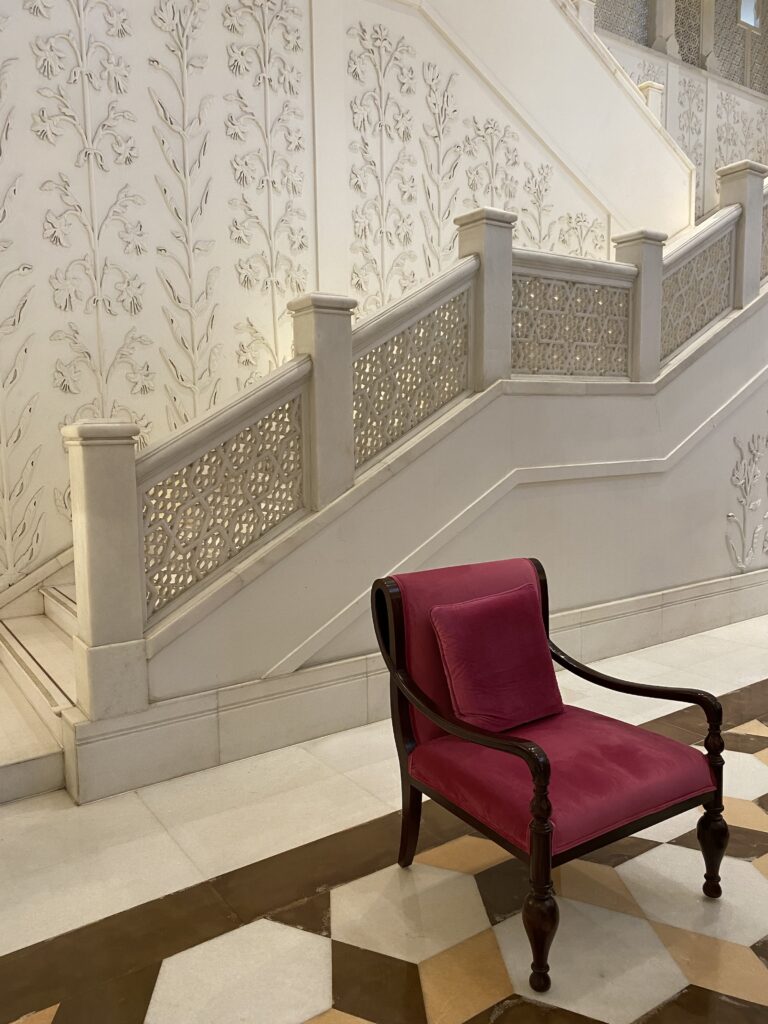 Ornate hotel lobby of the ITC Rajputana Hotel in Jaipur, India with a single fuchsia upholstered chair